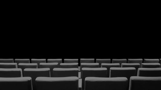 Empty theatre seats seen from the stage, the space above them in darkness.